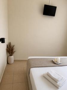 a white room with a bed and a tv on the wall at Aurelia Rooms in Ios Chora