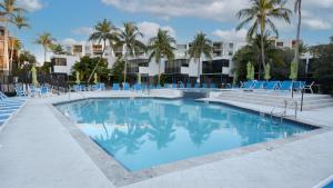 a swimming pool with blue chairs and palm trees at A409 Moon Bay in Key Largo