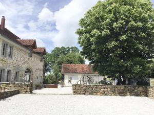 a tree in front of a building with a stone wall at L'Entre-Coeur in Ménétru-le-Vignoble