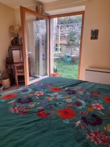 a bed with a green blanket with flowers on it at Chez Flo in Lamastre