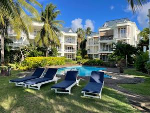 a resort pool with lounge chairs and palm trees at Résidence îlot in Grand-Baie
