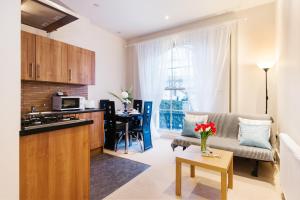 cocina y sala de estar con sofá y mesa en Elicia's South Kensington Apartment en Londres