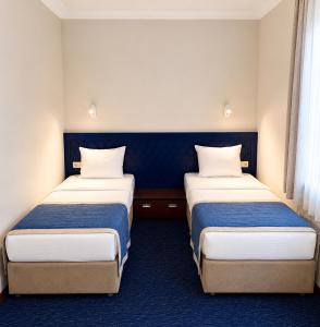 two beds in a small room with blue carpet at Cruise Hotel in Tbilisi City +35 photos