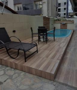 a deck with three chairs and a swimming pool at Intermares perto de tudo com 3 quartos in Cabedelo