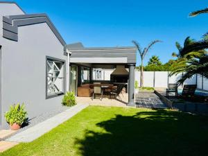 a white house with a patio with a grass yard at Hideaway Haven 2 in Cape Town