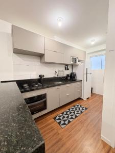 a kitchen with white cabinets and a black counter top at Apê aconchegante e climatizado - Villa Kennidy in Caruaru