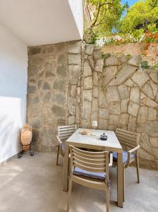 a table and chairs in front of a stone wall at Nefonas Guest House in Skiathos