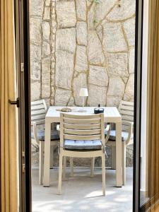 a table and chairs on a patio with a stone wall at Nefonas Guest House in Skiathos