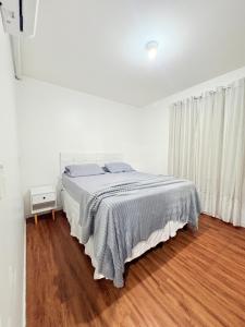 a white bedroom with a bed and a wooden floor at Apê aconchegante e climatizado - Villa Kennidy in Caruaru +11 photos