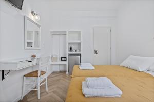 a small white room with two beds and a desk at Kamelia Hotel in Spetses