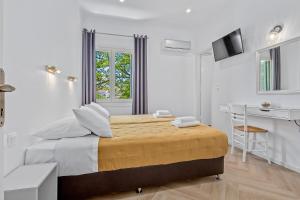 a white bedroom with a bed and a desk at Kamelia Hotel in Spetses