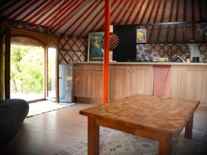 a room with a table and a kitchen with a refrigerator at Le Ptit Mas Yourte ou Logicube in Salernes