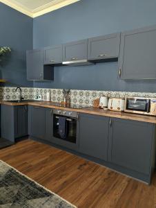 a kitchen with gray cabinets and a blue wall at Mulberry Lodge -- a luxury cottage on the West Highland Way in Drymen +20 photos