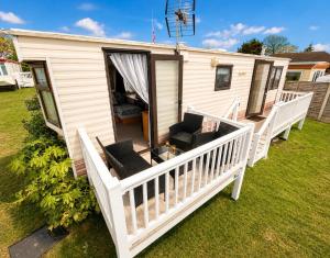 a mobile home with a porch and a deck at The Hemsbee Static caravan 117 Sandsgate Hemsby in Hemsby