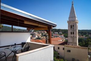 a balcony with a table and a church tower at Castello in Mali Lošinj