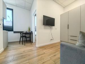a living room with a couch and a tv on a wall at POPIELATE Apartamenty in Żywiec