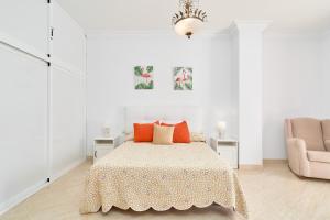 a white bedroom with a bed and a chair at Dúplex céntrico, 2 grandes terrazas in Nerja