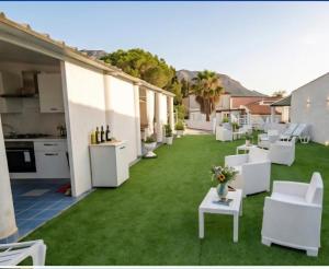 an outdoor patio with white chairs and grass at I Venti di Vulcano in Vulcano +19 photos