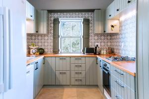 a kitchen with white cabinets and a window at Artful Hideaway with Pool & Fireplace in Riebeek-Kasteel +7 photos