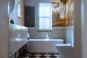 a white bathroom with a tub and a window at Artful Hideaway with Pool & Fireplace in Riebeek-Kasteel