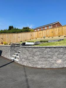 a stone retaining wall with a fence and a building at Ambermay House in Armagh