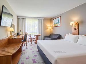 ein Hotelzimmer mit einem großen Bett und einem Schreibtisch in der Unterkunft Mercure Cieszyn in Cieszyn