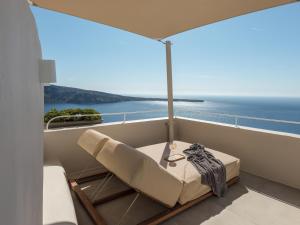a balcony with a chair and a table and the ocean at Art Maisons Oia Castle in Oia