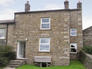 an old stone house with a bench in front of it at Lilac Cottage in Hawes