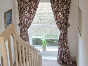 a window with a flowery curtain and a staircase at Lilac Cottage in Hawes