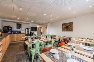 a restaurant with wooden tables and green chairs at Residhotel Mulhouse Centre in Mulhouse