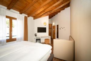 a bedroom with a white bed and a television at Hotel Il Castagno in Mugena