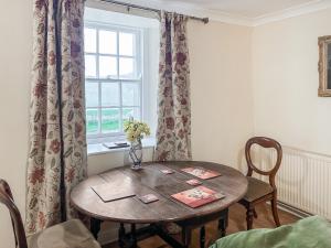 a dining room table with a vase of flowers on it at Foumartdean Cottage in Town Yetholm