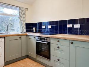 a kitchen with white cabinets and blue tiles at Foumartdean Cottage in Town Yetholm