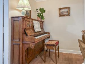 an old piano in a living room with a lamp at Foumartdean Cottage in Town Yetholm