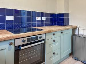 a kitchen with blue tiles on the wall at Foumartdean Cottage in Town Yetholm +11 photos