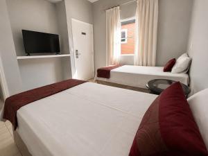 ein Hotelzimmer mit zwei Betten und einem Flachbildfernseher in der Unterkunft Hotel dos Lagos in Alfenas