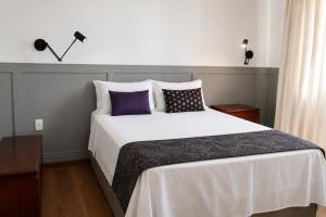 ein Schlafzimmer mit einem großen weißen Bett und lila Kissen in der Unterkunft Hotel dos Lagos in Alfenas