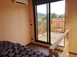 a room with a bed and a balcony with a deck at écolodge Aubépine in Leimbach