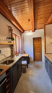 a kitchen with a sink and a wooden ceiling at Chalupa pri potoku in Zuberec