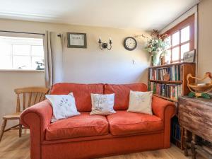 a living room with a red couch with pillows at The Old Tack Room - Uk49233 in Tilshead