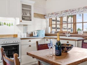 a kitchen with a bottle of wine on a table at Gardeners Cottage in Putley