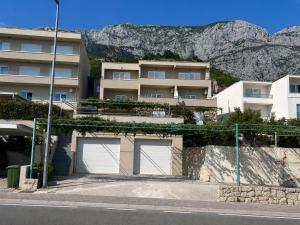 a building with two garage doors in front of a mountain at Apartmani Tomaš in Tučepi