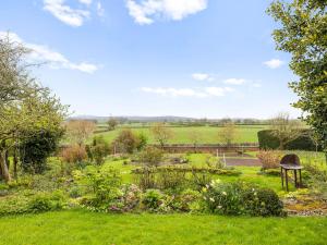 a garden with a bench and flowers in the grass at Gardeners Cottage in Putley