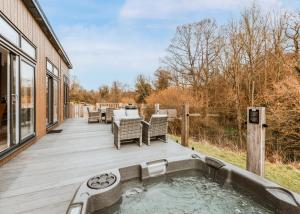 a deck with a hot tub and a table and chairs at The Astbury Golf And Lodge Resort in Bridgnorth