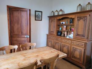a dining room with a wooden table and a wooden hutch at La Ferme des Coquelicots in Miraumont