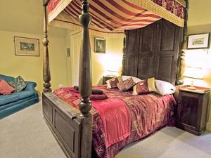 a bedroom with a canopy bed and a blue couch at Lochside Stable Hse in Town Yetholm