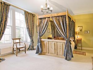 a bedroom with a canopy bed and a window at Lochside Stable Hse in Town Yetholm