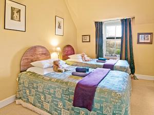 two babies sitting on two beds in a bedroom at Lochside Stable Hse in Town Yetholm