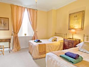 a bedroom with two beds and a window at Lochside Stable Hse in Town Yetholm