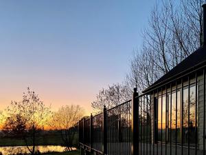 a fence in front of a building with the sunset in the background at Talltrees - Uk42842 in Uplowman +16 photos